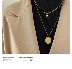 Detail of double-layer gold titanium steel necklace with star and sun charms on a model
