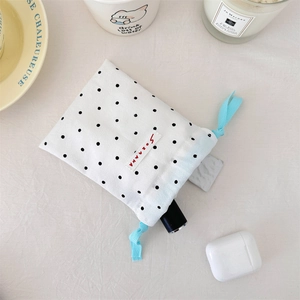 Polka dot drawstring storage bag with blue woven rope and makeup items inside