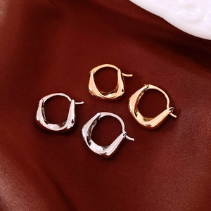Detailed top view of gold and silver plated oval textured earrings on silk fabric
