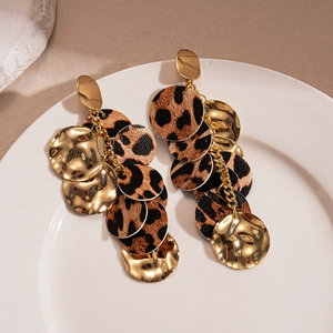 Chic leopard print and wavy gold layered drop earrings on a white ceramic plate