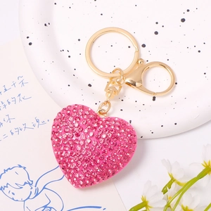 Detailed view of pink rhinestone heart keychain with gold ring on a lifestyle background