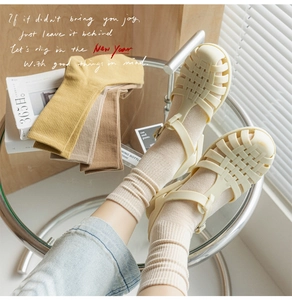 Detail of cream Roman woven sandals paired with beige ribbed socks in a warm home setting