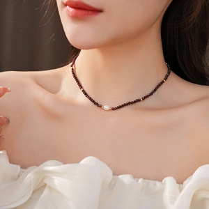 Close-up of garnet bead necklace with a white freshwater pearl and gold accents