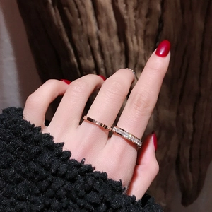 Detail of rose gold rings with cubic zirconia stones worn on finger with red nails