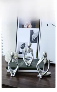 Detailed close-up of three silver abstract thinker sculptures on a modern wooden table