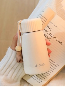Mini cream-white thermal cup with non-slip screw cap and leather tassel lanyard detail