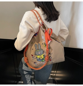 Detail of khaki canvas tote with cartoon rabbit print and orange rope shoulder straps