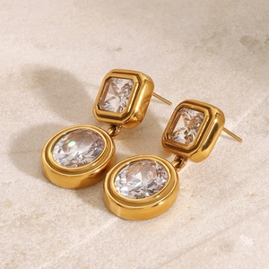 Detailed view of gold earrings featuring rectangular and oval white cubic zirconia stones