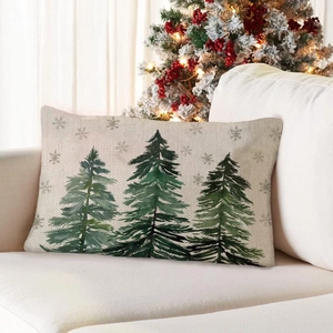 Detail of linen Christmas pillow case with green trees and snowflakes on a cozy sofa