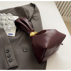 Close-up of burgundy leather bucket bag with a gold ring clasp on a stylish suit
