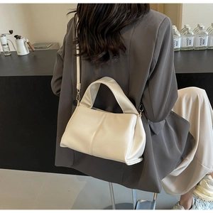 Close-up of the beige leather bag texture and handle detail shown on a model outfit