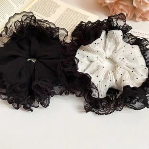 Vue détaillée de chouchous en dentelle noire et mousseline à pois blancs sur table