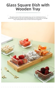 Detail of square glass snack bowls with gold rims on a bamboo tray set on a green table