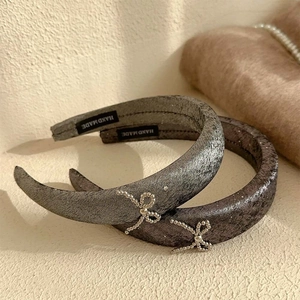 Pair of gray velvet headbands with silver beaded bows on a warm textured background