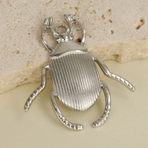Macro view of 304 stainless steel beetle pendant with detailed engravings on stone background