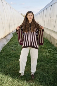 Outdoor shot of a woman in a loose striped knit sweater and white cotton pants
