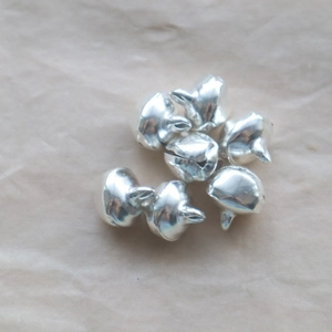 Macro shot of silver metal bell accessories on a light brown textured background