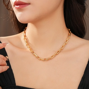 Close-up of golden chain necklace worn by a model showcasing sleek minimalist design