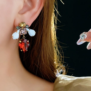 Vintage style gold earring with multi-colored crystals and a red drop stone on a model