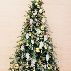 Detailed view of clear acrylic pinecone ornaments hanging on a green Christmas tree