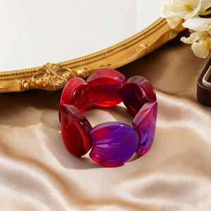 Macro view of red and purple marbled acrylic resin bracelet on luxury champagne silk