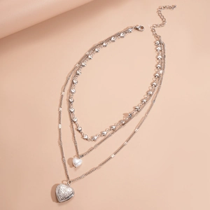 Detailed view of triple-layer silver necklace with heart pearl and floral relief charms