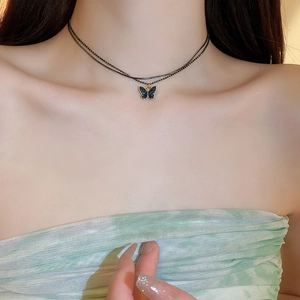 Close-up of double-layer choker necklace with blue butterfly pendant on a model