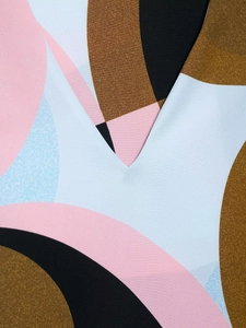 Primer plano del escote en V con estampados de plumas geométricas en azul y rosa