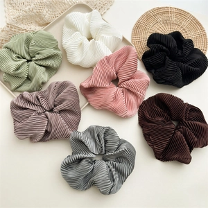 Detailed view of seven pleated hair scrunchies in elegant morandi colors and silky texture