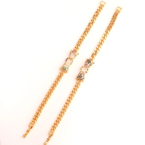 Macro detail of gold-plated Cuban link bracelet with dual leopard heads and colored zircons