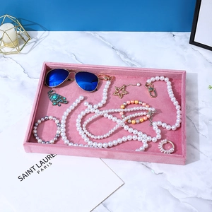Top view of pink velvet jewelry tray with various accessories on marble surface