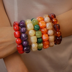 Detail of chunky acrylic bracelets featuring colorful irregular marbled beads on a model