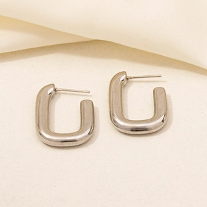 Detailed close-up of pair of silver 304 stainless steel C-shaped stud earrings on fabric