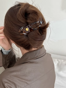 Detail of tortoise shell hair claw clip with gold fashion ornament on a bun