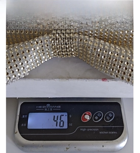 Macro detail of champagne gold rhinestone mesh ribbon showing weight on digital scale