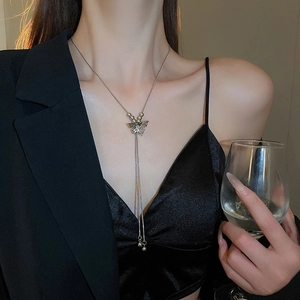 Close-up of a silver butterfly tassel necklace worn by a model in elegant attire