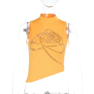 Détail du haut orange à col montant avec motif rose en strass et ourlet asymétrique