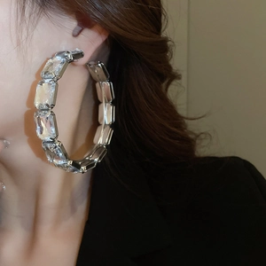 Macro detail of silver oversized hoop earrings featuring rectangular crystal embellishments