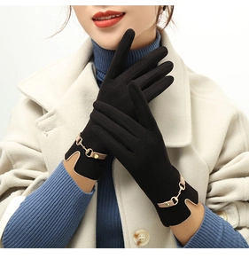 Detail of black winter gloves with gold chain accent and camel leather trim on the wrist