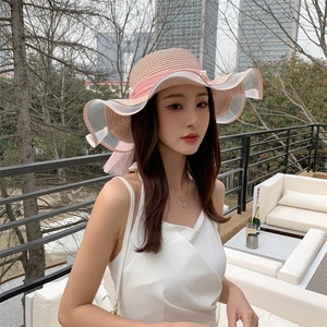 Detail of wide brim straw hat featuring pink ribbon, pearls and white mesh lace trim