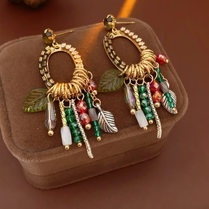 Macro shot of boho leaf drop earrings with colorful beads on brown velvet jewelry box