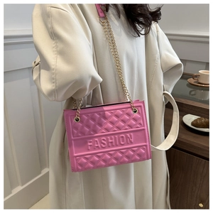 Detail of pink quilted shoulder bag featuring embossed fashion lettering and gold chain