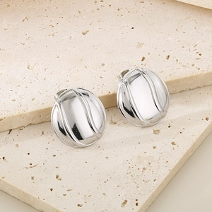 Close-up of silver round stud earrings with streamlined wave texture on stone background