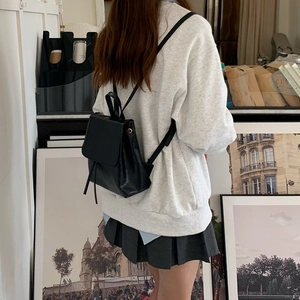 Dettaglio di un mini zaino in pelle nera con coulisse indossato da una modella