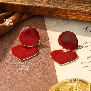 Detailed view of red enamel earrings with gold edges and vintage background setup