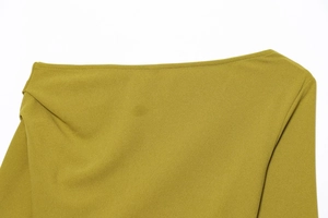 Primo piano del top asimmetrico giallo senape che mostra la trama del tessuto e le cuciture