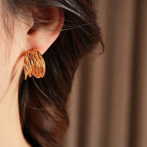 Polished gold plated multi-layer spiral hoop earrings worn on ear with luxury aesthetic