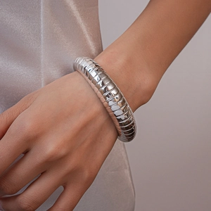 Detail shot of silver segmented thick bangle with high-gloss metallic finish for women