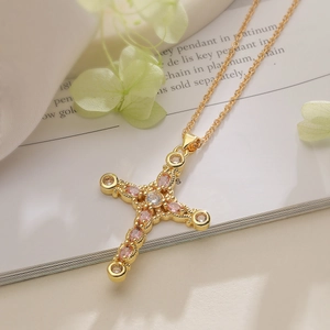 Detailed macro of gold-plated cross pendant with pink and clear zircon stones on a fine chain