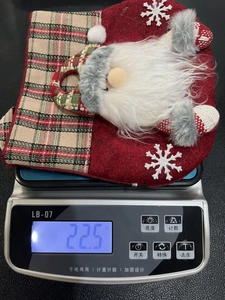 Detail of Christmas felt gift bag with Santa Claus motif and red plaid trim showing 22.5g weight